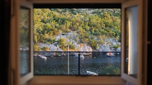 A window with a view of a lake surrounded by rocky hills and trees. - Serene Family Villa by the Rogoznica Coast (Rogoznica)