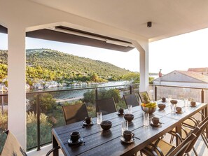 A dining table set with cups, bowls, and glasses, overlooking a river and hills. - Serene Family Villa by the Rogoznica Coast (Rogoznica)