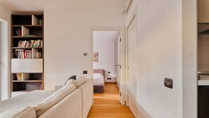 A narrow hallway with a bed, a bookshelf, and a door leading to another room. - Hostmate - Milano - Ulpio Traiano (Milano)