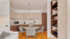 A modern kitchen with a dining area, wooden flooring, and a built-in bookshelf. - Hostmate - Milano - Ulpio Traiano (Milano)