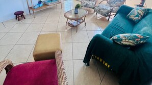 A spacious living area with a television, wicker furniture, and a view of the outside. - Cozy and charming house 300 meters from Indaiá Beach, in Bertioga. (Bertioga)