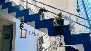 A modern interior with a blue staircase, a glass ceiling, and potted plants. - Cozy and charming house 300 meters from Indaiá Beach, in Bertioga. (Bertioga)