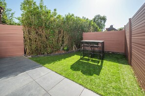 Ein Garten mit Terrasse, Tisch und Stuhl.