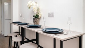 A kitchen with a long island table, stools, and white orchids. - Modern Luxury 4Bdrm 15 min to LDN centre | Business/Vacay | Parking onsite (London)