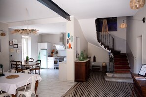 A modern kitchen with white cabinets, a dining area with a table and chairs, and a staircase leading to a second floor. - Charming Provencal farmhouse with swimming pool and jacuzzi  sleeps up to 8 🌿☀️ (Loriol-du-Comtat)