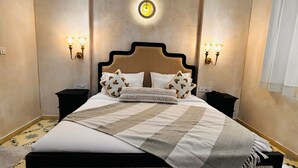 A neatly arranged bedroom with a large bed, two bedside tables, and wall-mounted lighting. - SADRI HAVELI Boutique Heritage Hotel - Lake Pichola Udaipur (Udaipur)