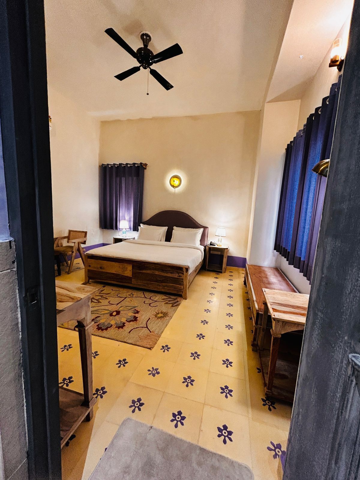 Ein Schlafzimmer mit einem Bett, Nachttischen, einem Schreibtisch, einem Deckenventilator und einer Wandleuchte.