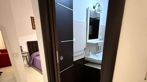 Een moderne badkamer met een donkere deur, witte tegels en een spiegel boven de wastafel.