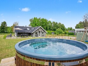 A hot tub with a wooden deck, a house with a patio, and a fenced yard. - "Hielm" - 490m from the sea by Interhome (Tranekær)