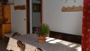 A dining area with a table set for four, wooden chairs, a wooden cabinet, and a potted plant. - Gio's house, apartment with garden and barbecue, relaxation in the midst of nature (ville sur sarre)