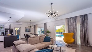 Ein modernes Wohnzimmer mit einer Couch, einem gelben Sessel und einem Essbereich im Hintergrund.