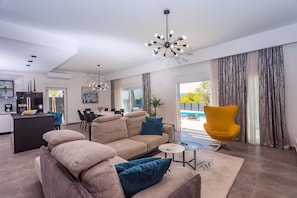 A modern living room with a sofa, a yellow chair, and a dining area in the background. - Luxury Villa Retreat in Sestanovac (Sestanovac)