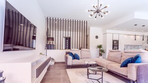 Ein modernes Wohnzimmer mit einer Couch, einem Couchtisch und einem an der Wand befestigten Fernseher.