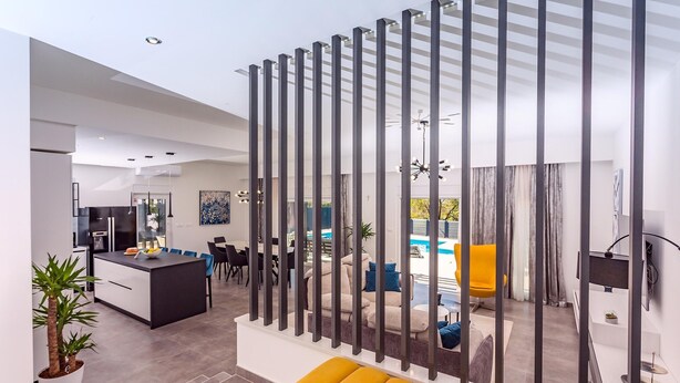 Ein moderner Wohnraum mit Küche, Essbereich und Blick auf einen Pool.
