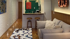 Un interior moderno con un sofá, una mesa de centro, una zona de cocina y un letrero en la pared.