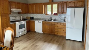 Una cocina con armarios de madera, una estufa blanca, un lavavajillas y un refrigerador.