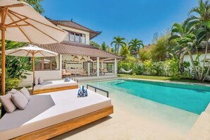 A modern villa with a swimming pool, outdoor seating, and lush tropical vegetation. - Villa Baladeva - 5BDR luxury villa, huge pool (Kuta)