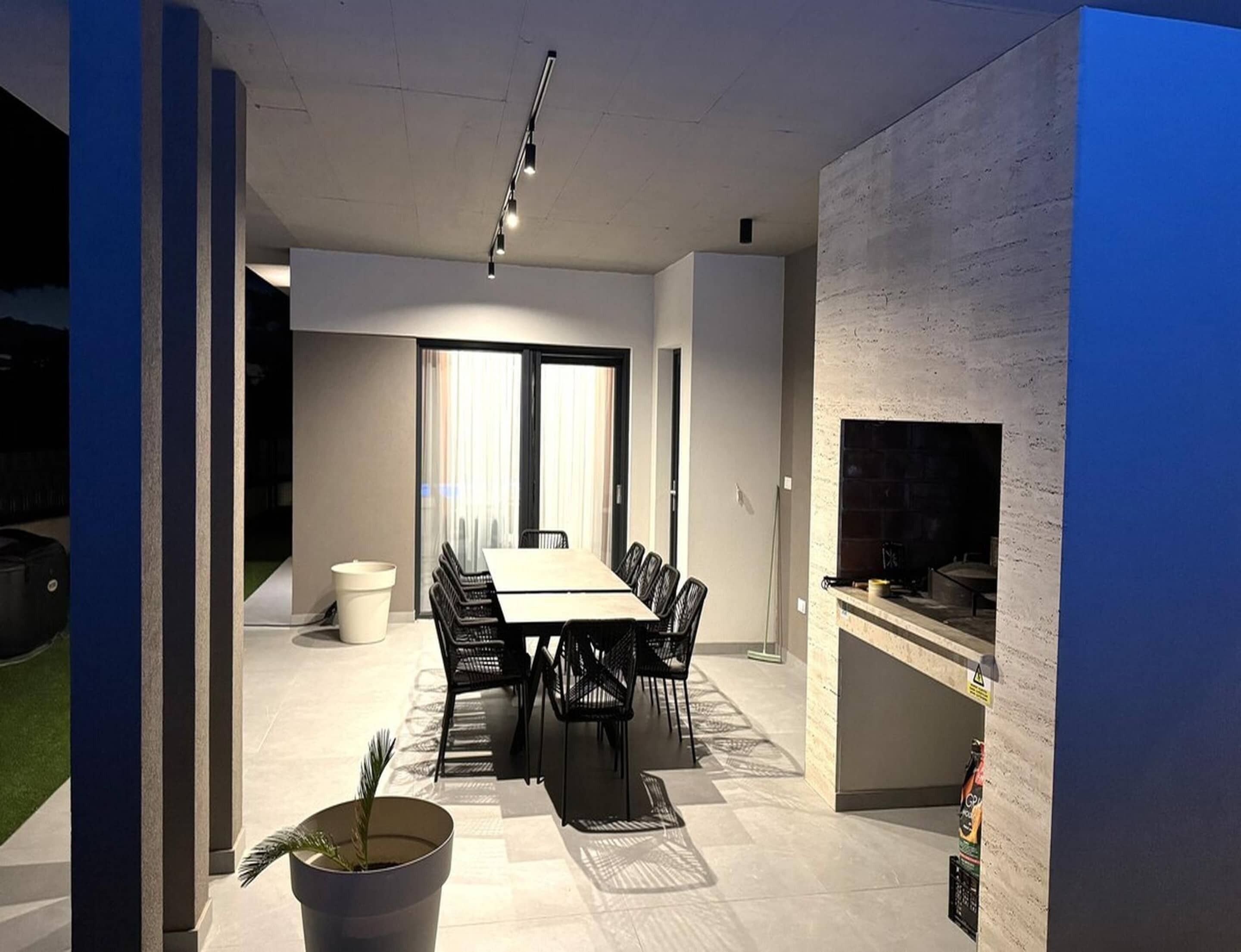 Un comedor moderno con una mesa larga, sillas, una planta en maceta y una chimenea.