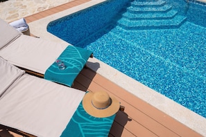 Bereich eines Pools mit Liegestühlen und einem Hut auf dem Deck.