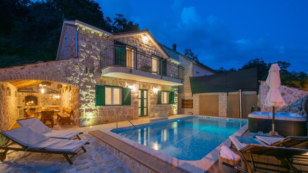 Un edificio in pietra con piscina, area salotto esterna e vasca idromassaggio.