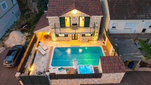 Una casa in pietra su due piani con piscina, area salotto esterna e vasca idromassaggio.