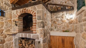 Un camino in pietra con arco in mattoni, un camino a legna e una pila di legna da ardere.
