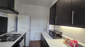 Eine moderne Küche mit Gasherd, weißem Kühlschrank, schwarzen Schränken und einem Toaster.
