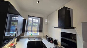 A modern kitchen with a built-in stove, a sink, and a window with blinds. - Free Parking + Modern 1BR Near Central London (Greater London)