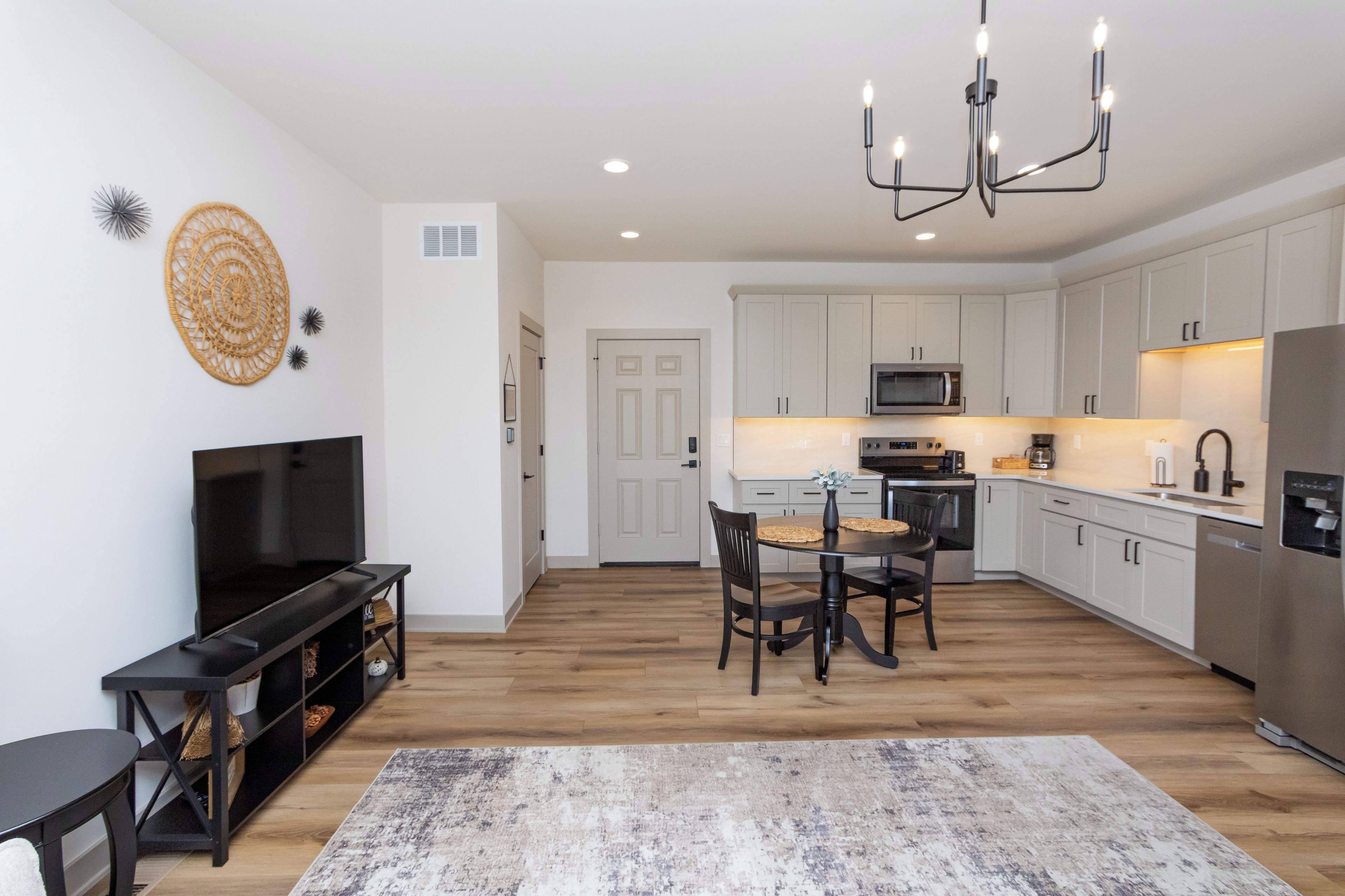 A modern kitchen with white cabinets, a built-in microwave, and a stainless steel refrigerator.