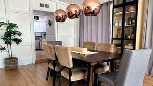 Een eetgedeelte met een houten tafel, zes stoelen en drie koperen hanglampen.