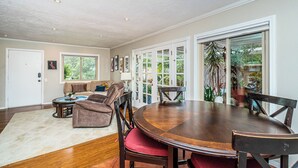 A spacious living room with a large dining table, comfortable seating, and a view of the outdoors. - Fully Furnished 2BR Extended Stay Near UCSD & Scripps. Private Patio & Spa Bath (San Diego)