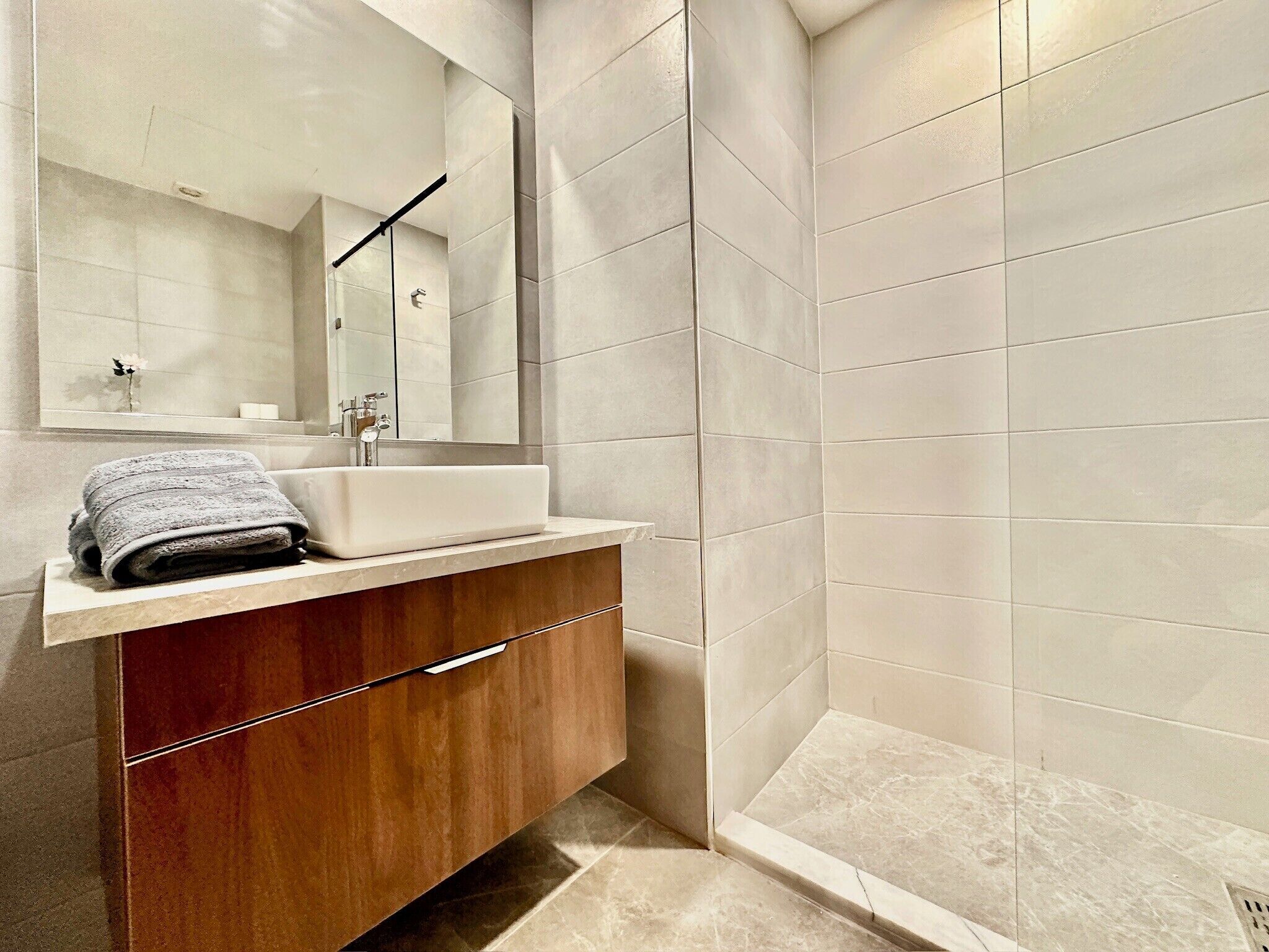 A modern bathroom with a sink, mirror, and shower area.