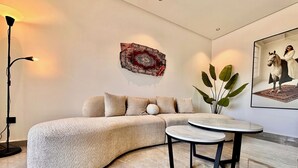Ein modernes Wohnzimmer mit einem gebogenen Ecksofa, einem runden Couchtisch und einer Stehlampe.