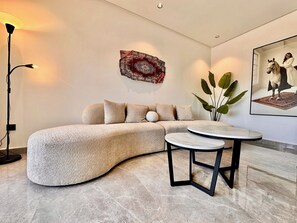 A modern living room with a curved sectional sofa, a round coffee table, and a floor lamp. - Cocon Elégant CFC, Pool, Gym & Parking Gratuit (Casablanca)