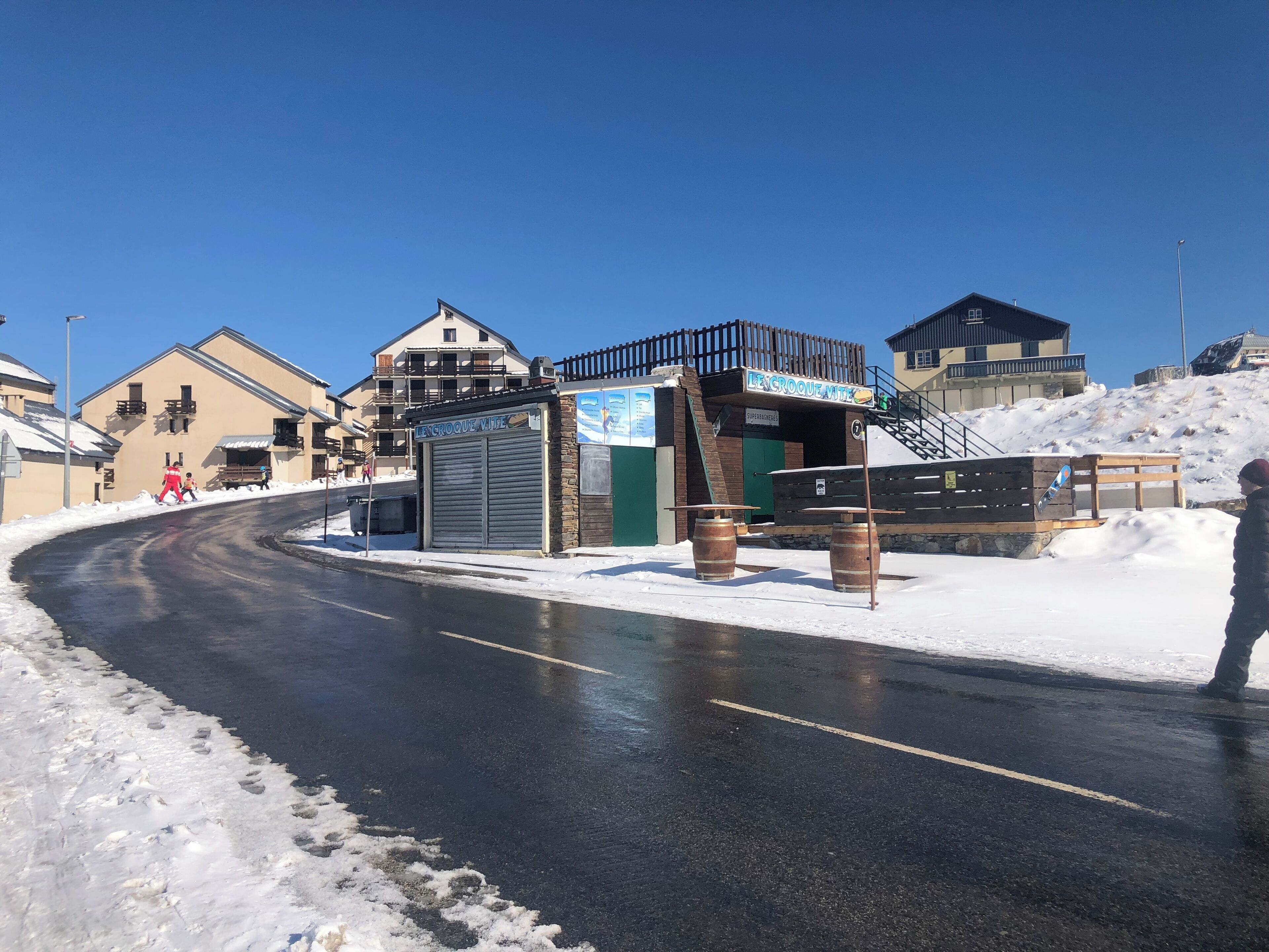 A ski resort with a closed ski lift, wooden benches, and a snow-covered road.