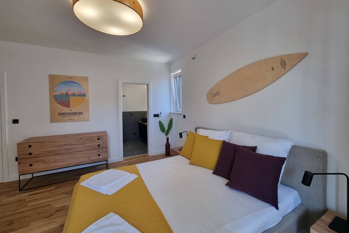 Un dormitorio moderno con una cama, mesita de noche y una decoración de tabla de surf en la pared.