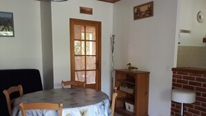 Un coin repas avec une table ronde et des chaises, un buffet en bois et une cheminée en briques.
