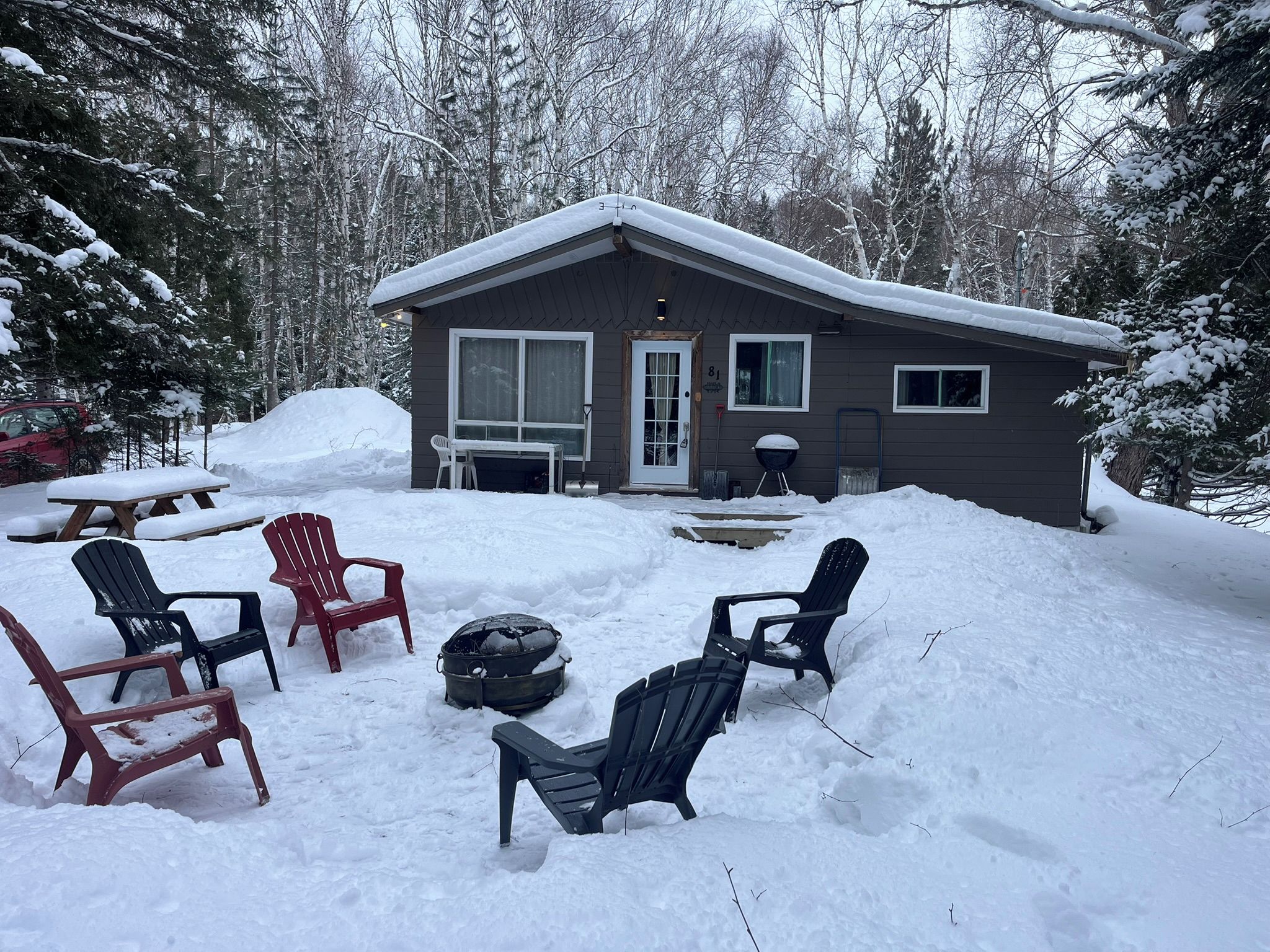 A cabin with a covered patio area, surrounded by snow-covered trees.