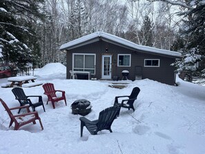 A cabin with a covered patio area, surrounded by snow-covered trees. - Chalet La grenouillère, Lac Taureau (Saint-Michel-des-Saints)