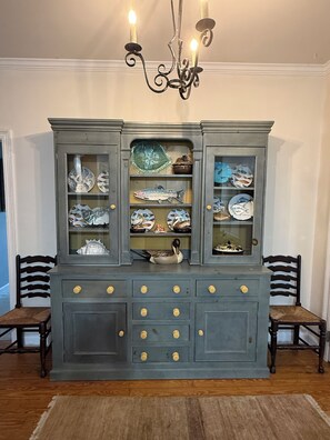 A dark blue cabinet with glass doors, displaying various dishes and a duck figurine.