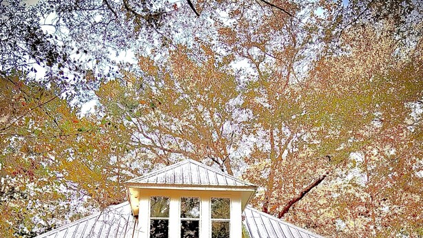 Ett tvåvåningshus med en veranda, en röd dörr och en flagga.