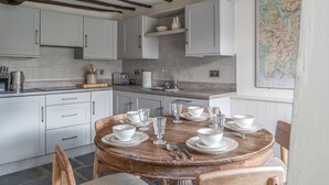 Cozinha com armários brancos, mesa de jantar de madeira para seis pessoas e um mapa na parede.