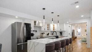 A modern kitchen with a large island, stainless steel appliances, and pendant lighting. - Luxury 7BR Rowhouse with Rooftop, Patio & Parking (Washington)