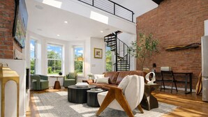 A spacious living room with a modern sofa, a coffee table, and a staircase leading to an upper level. - Luxury 7BR Rowhouse with Rooftop, Patio & Parking (Washington)