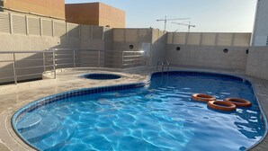 A swimming pool with a tiled edge, a metal ladder, and a few orange rings in the water. - Beautiful Bedroom in AlBarsha Near Metro (Dubai)