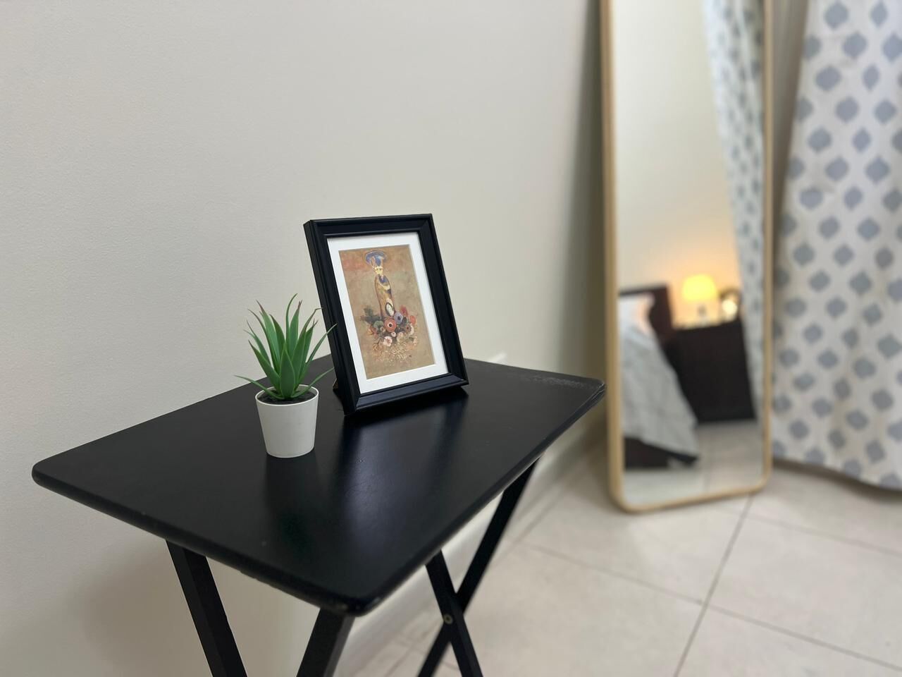 A small black table with a framed picture and a potted plant.