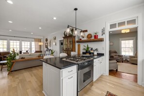Una cocina amplia con una isla central, muebles blancos y una estufa moderna.