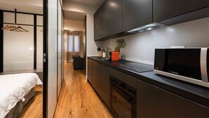 Una cocina moderna con armarios oscuros, un microondas y una encimera con tetera y cafetera.