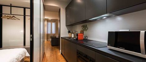 A modern kitchen with dark cabinetry, a microwave, and a countertop with a kettle and coffee maker.