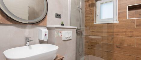 Une salle de bain moderne avec un grand lavabo ovale, des toilettes, une douche à parois de verre et un mur en bois.